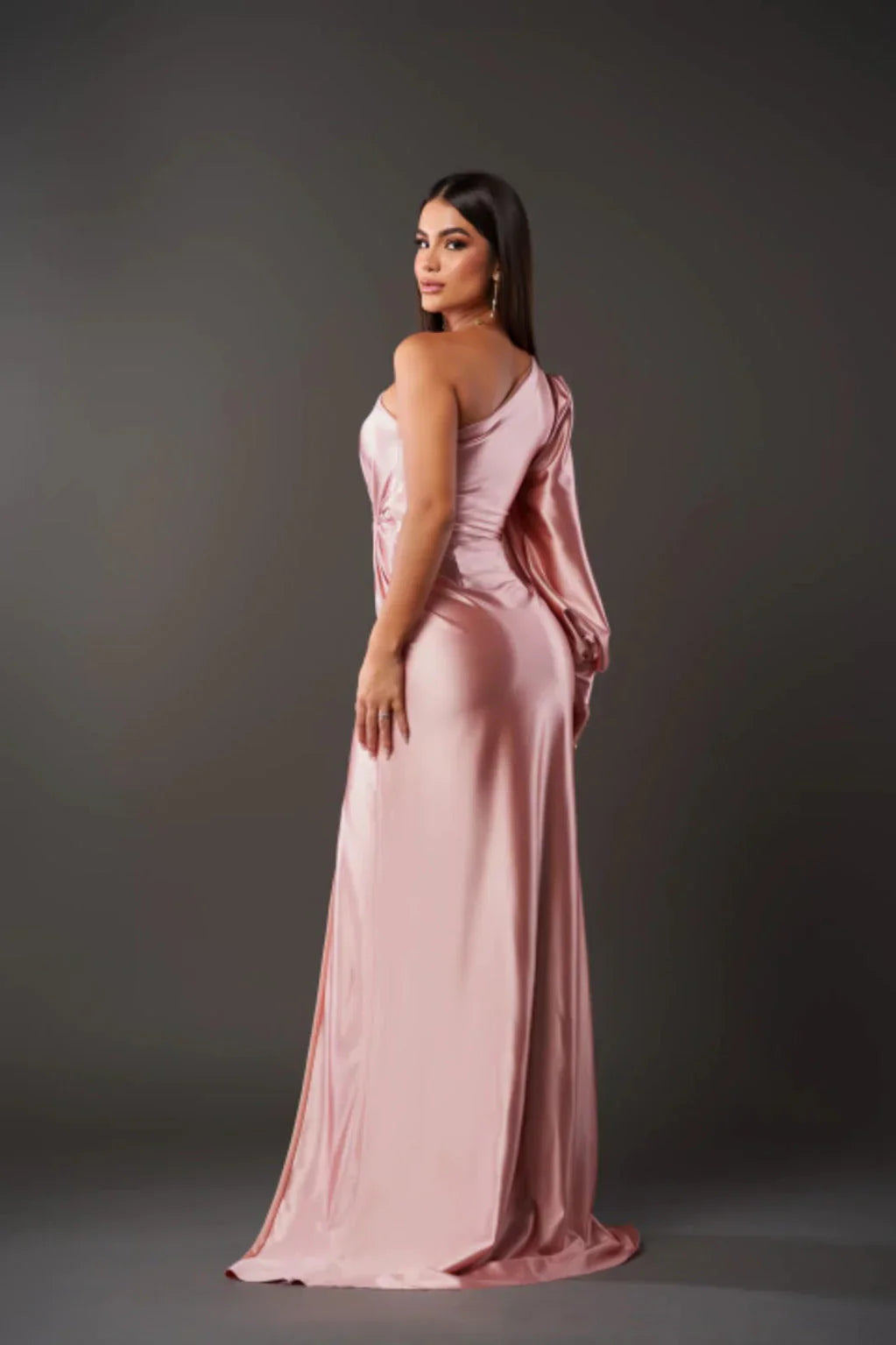 Woman wearing a pink evening gown against a gray background