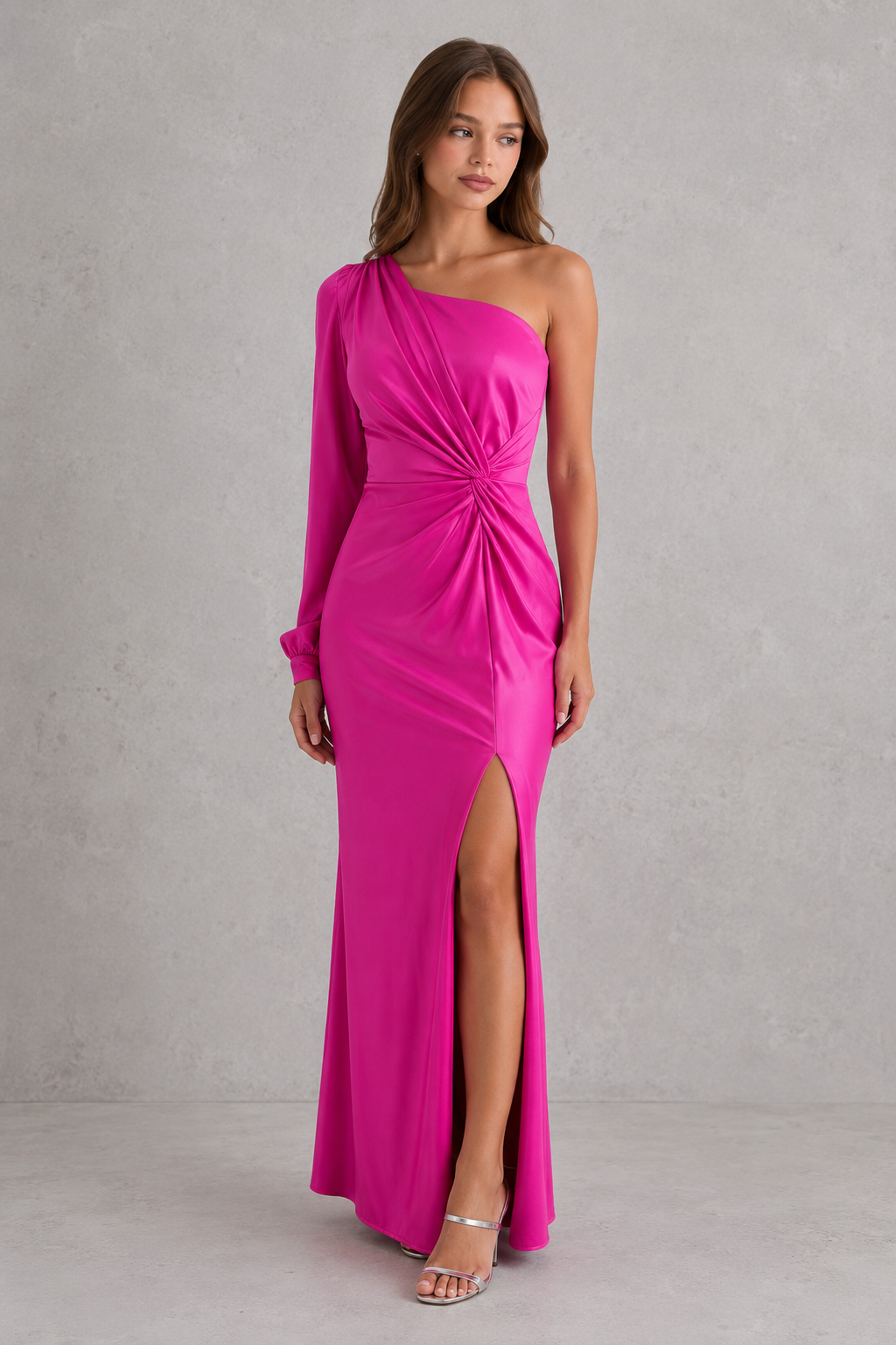 Woman wearing a bright pink one-shoulder dress with a slit on a gray background