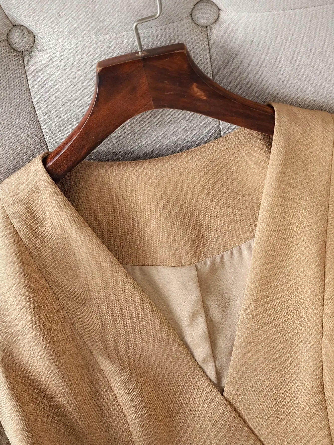 Beige coat on a wooden hanger against a neutral background