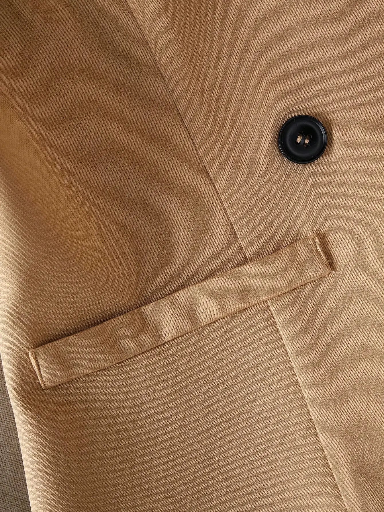 Close-up of a beige coat with a button and lapel detail