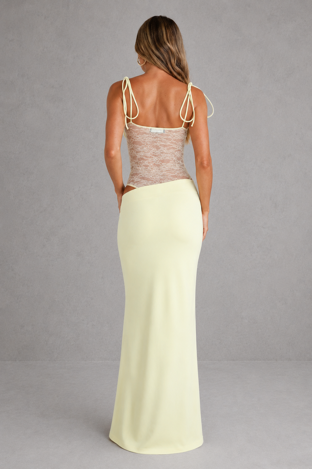 Woman wearing a two-piece outfit with a top and long skirt on a gray background
