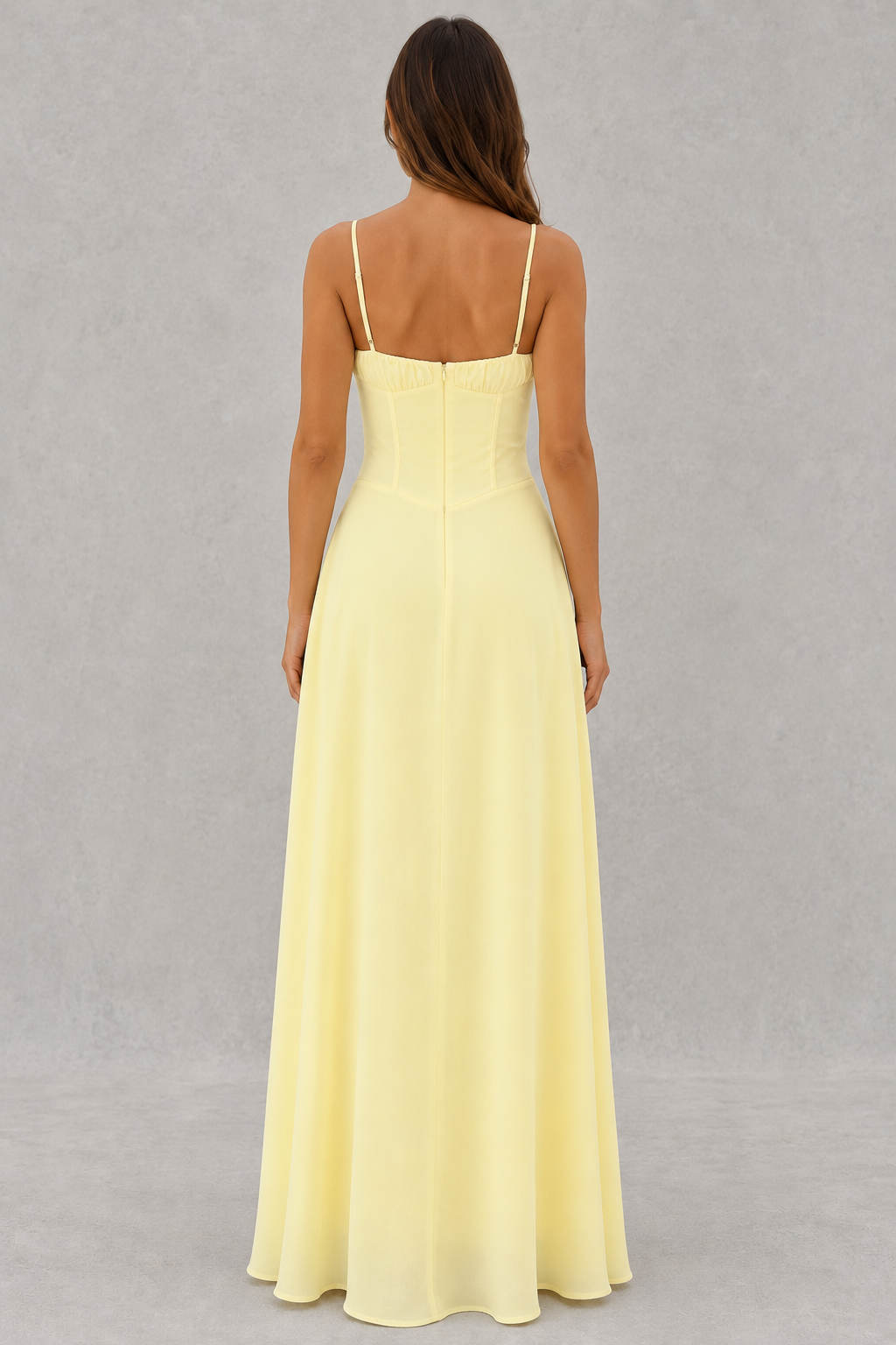 Woman wearing a light yellow dress with thin straps on a gray background