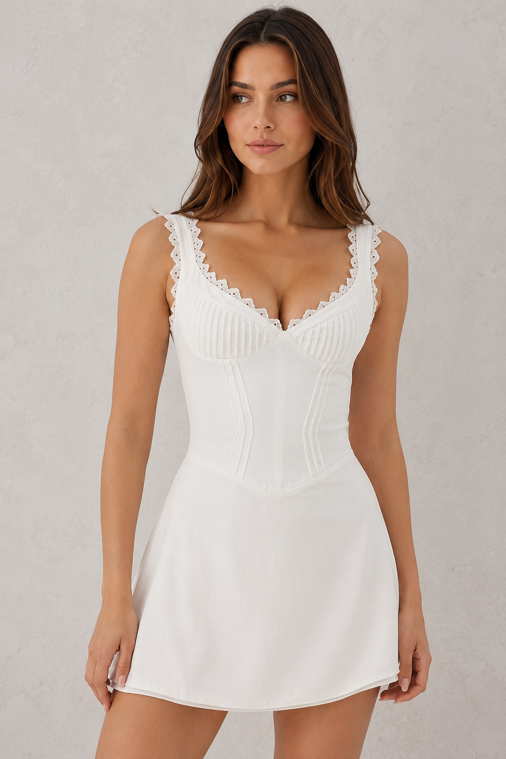 Woman wearing a white dress with lace details on a plain background