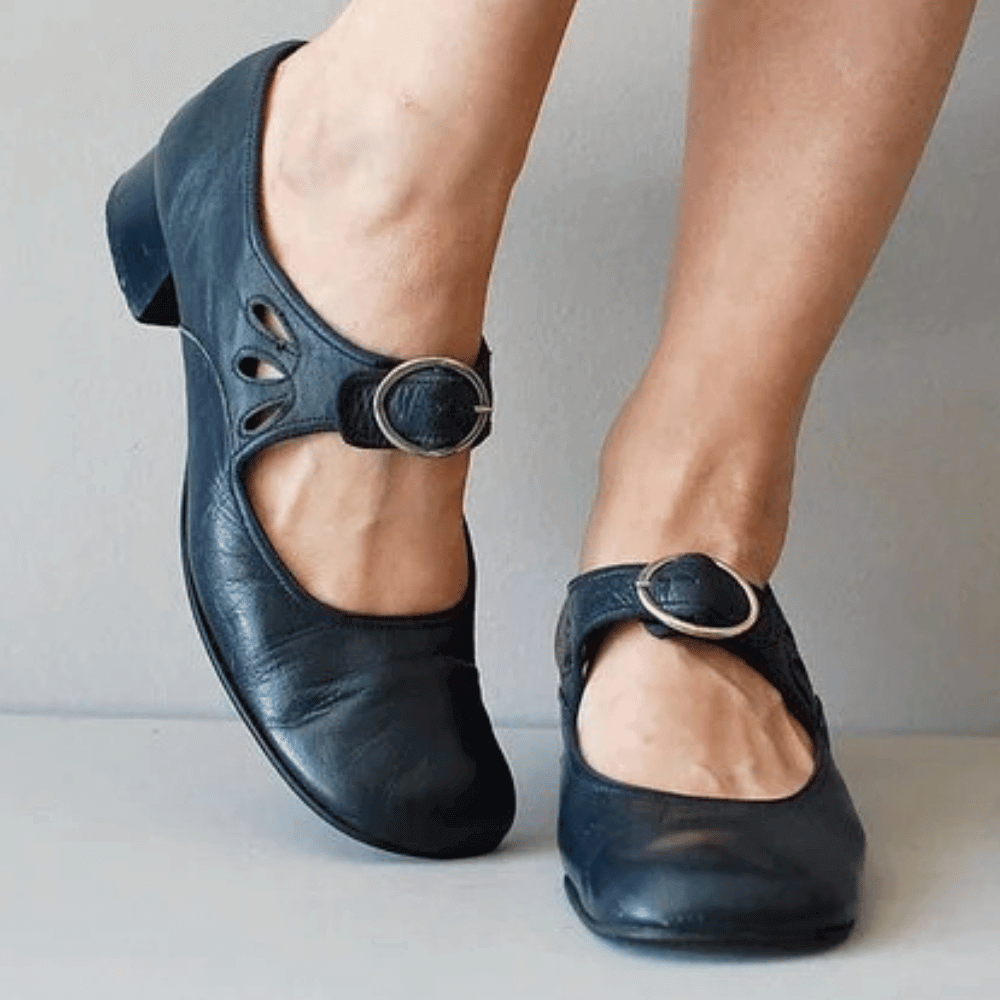 Black shoes with buckles worn by a person on a light background