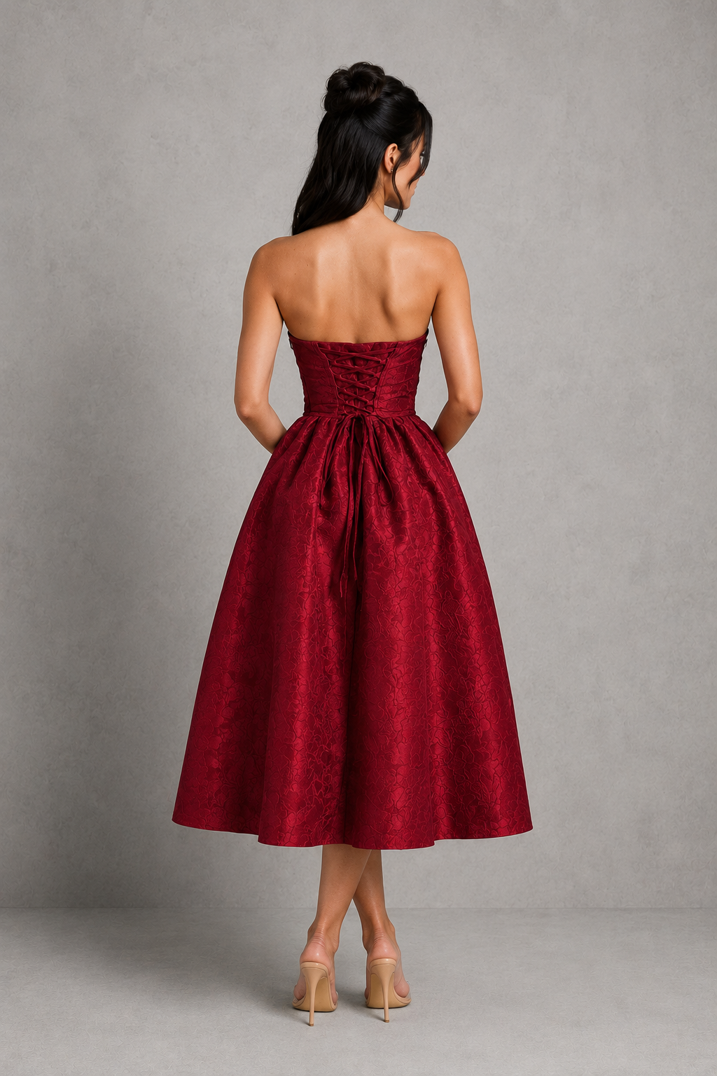 Woman wearing a strapless red dress against a gray background