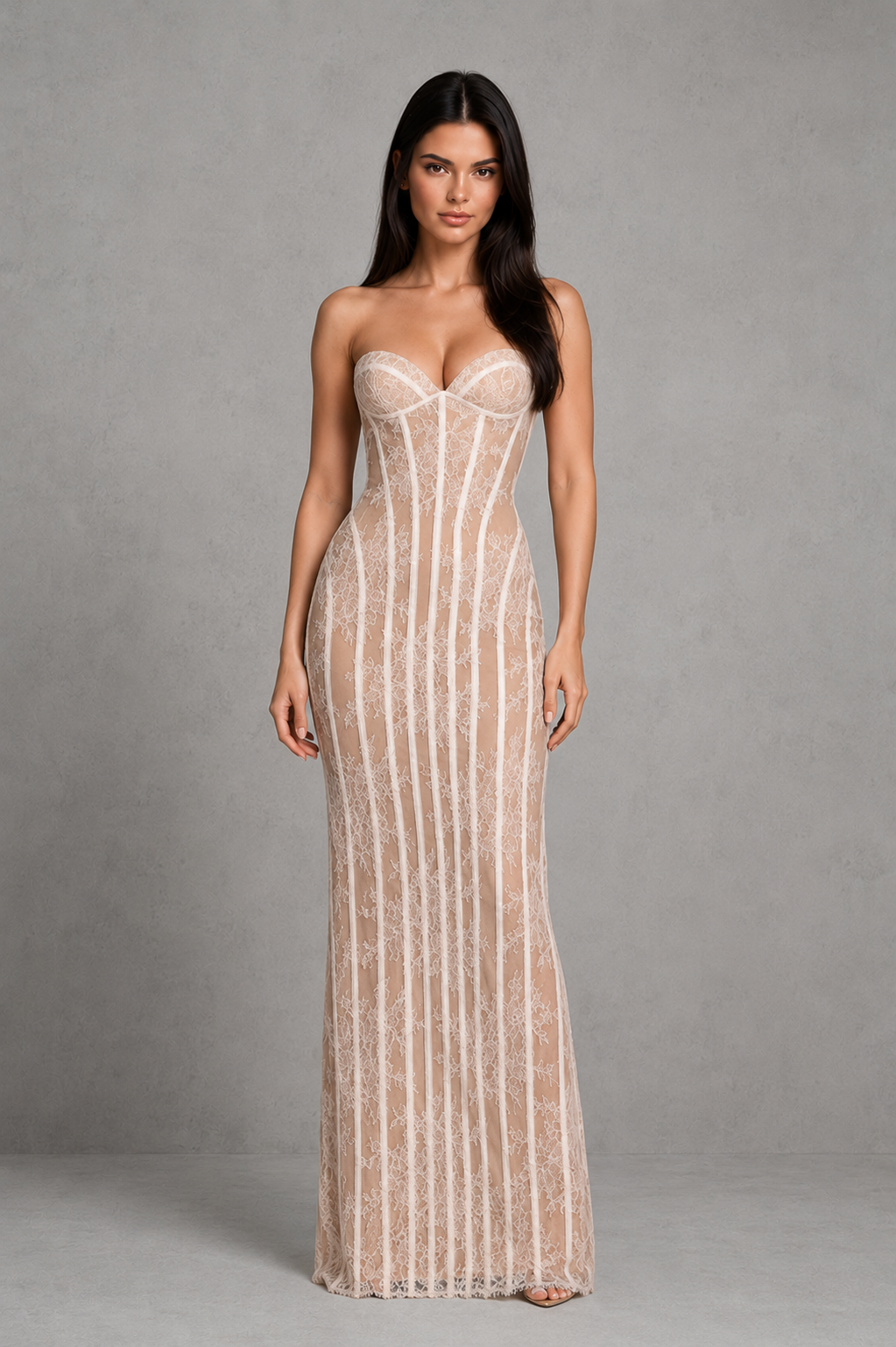 Woman wearing a strapless, long, beige lace dress against a gray background
