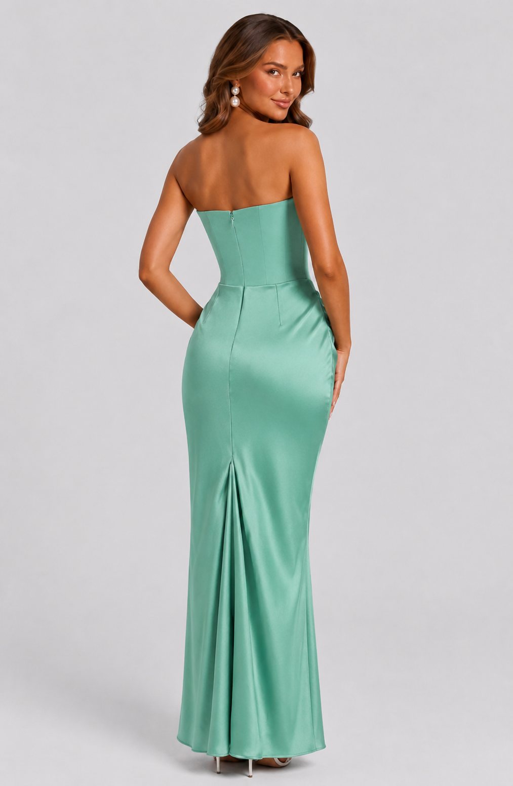 Woman wearing a strapless green evening gown on a light gray background