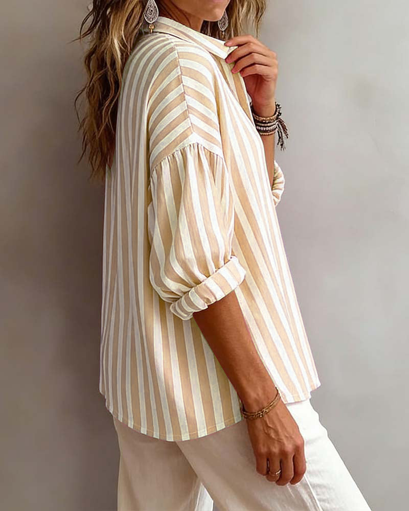 Woman wearing a striped shirt and white pants against a neutral background
