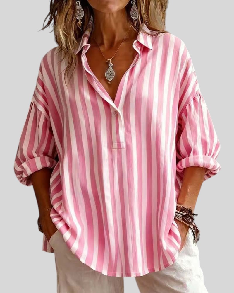 Person wearing a pink and white striped shirt with rolled-up sleeves on a plain background