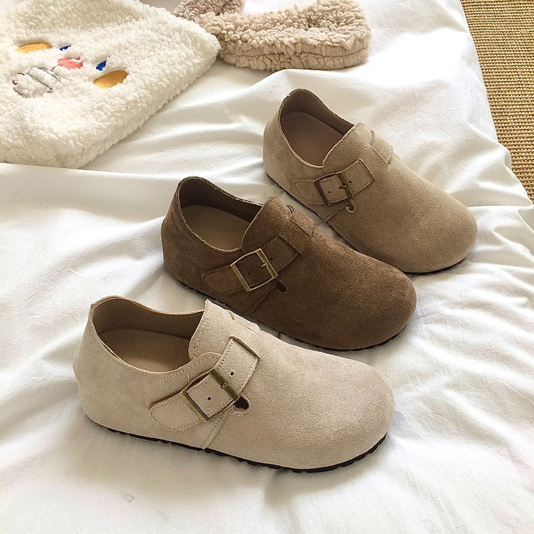 Pair of beige shoes with buckles on a white surface