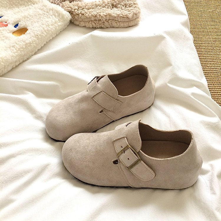 Pair of beige shoes with buckles on a white surface