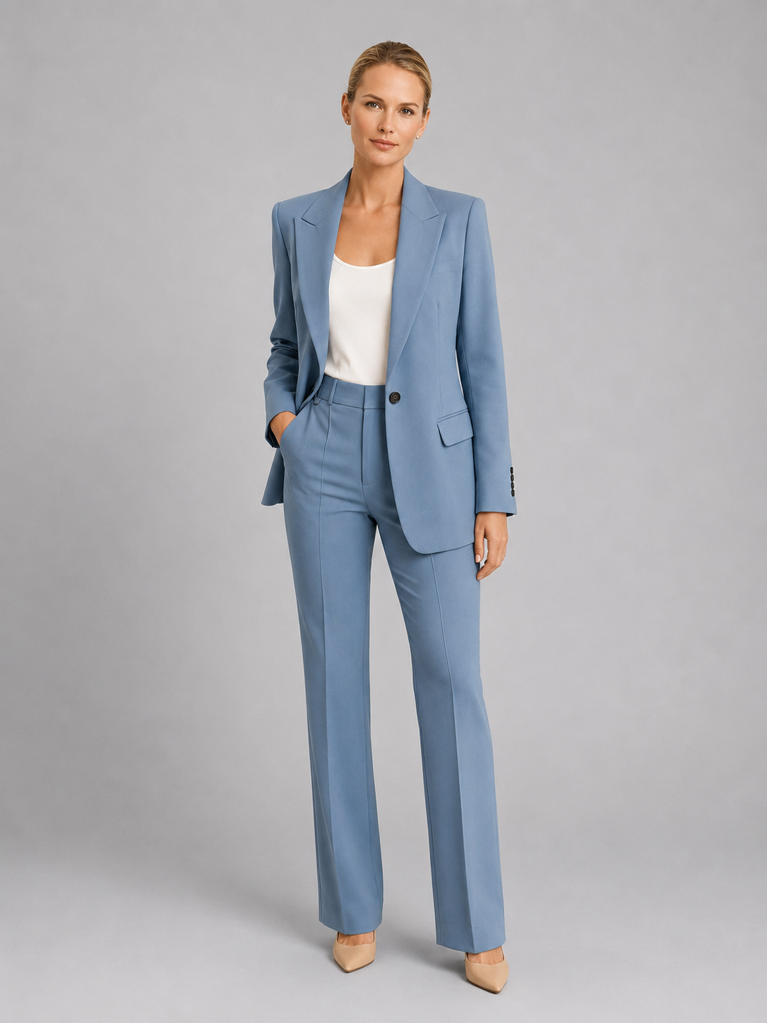 Woman wearing a light blue suit with a white top on a gray background