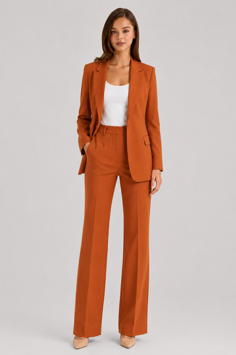 Woman wearing a rust-colored suit with a white top on a light gray background