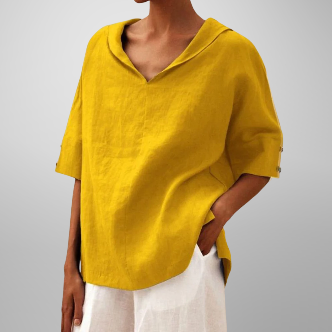 Person wearing a yellow linen top with rolled-up sleeves on a gray background