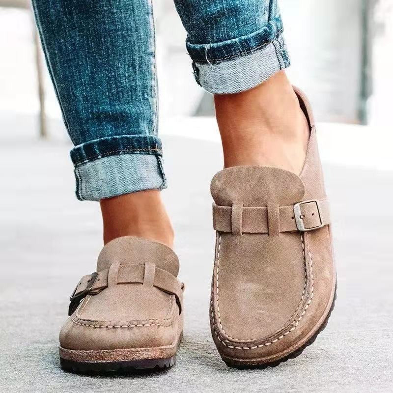 Brown loafers worn with rolled-up jeans on a light background