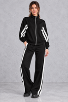 Women's black zip-up tracksuit set with white side stripes – front view