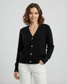 Black cardigan with gold heart buttons worn by a person on a light gray background