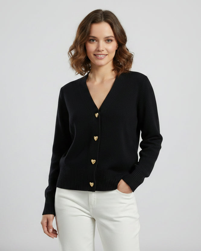 Black cardigan with gold heart buttons worn by a person on a light gray background