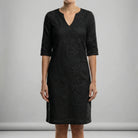 Black lace dress worn by a person on a gray background