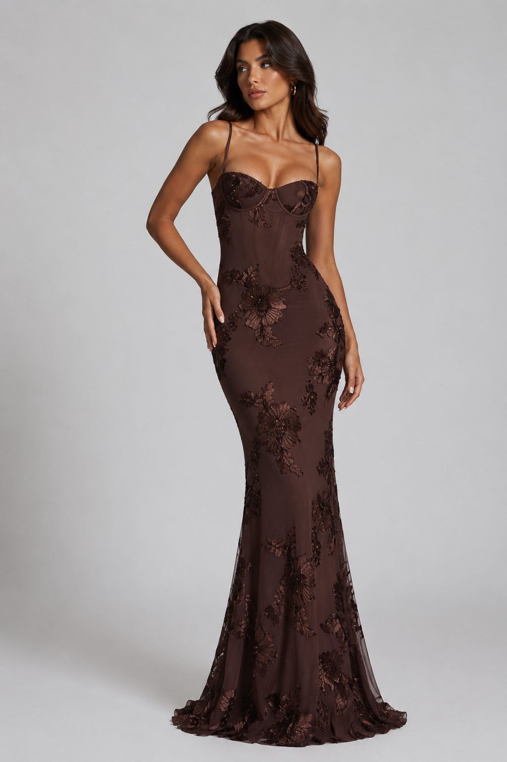 Woman wearing a brown floral evening gown against a gray background
