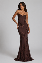 Woman wearing a brown floral evening gown against a gray background