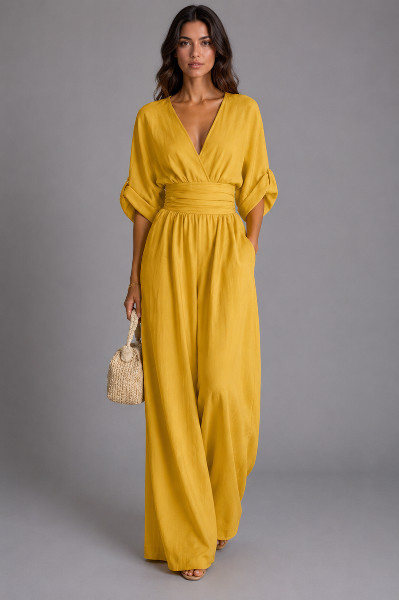 Woman wearing a yellow dress holding a woven bag against a gray background