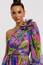 Woman wearing a colorful floral one-shoulder dress against a white background
