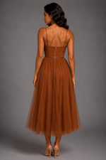 Woman wearing a brown dress with thin straps on a gray background
