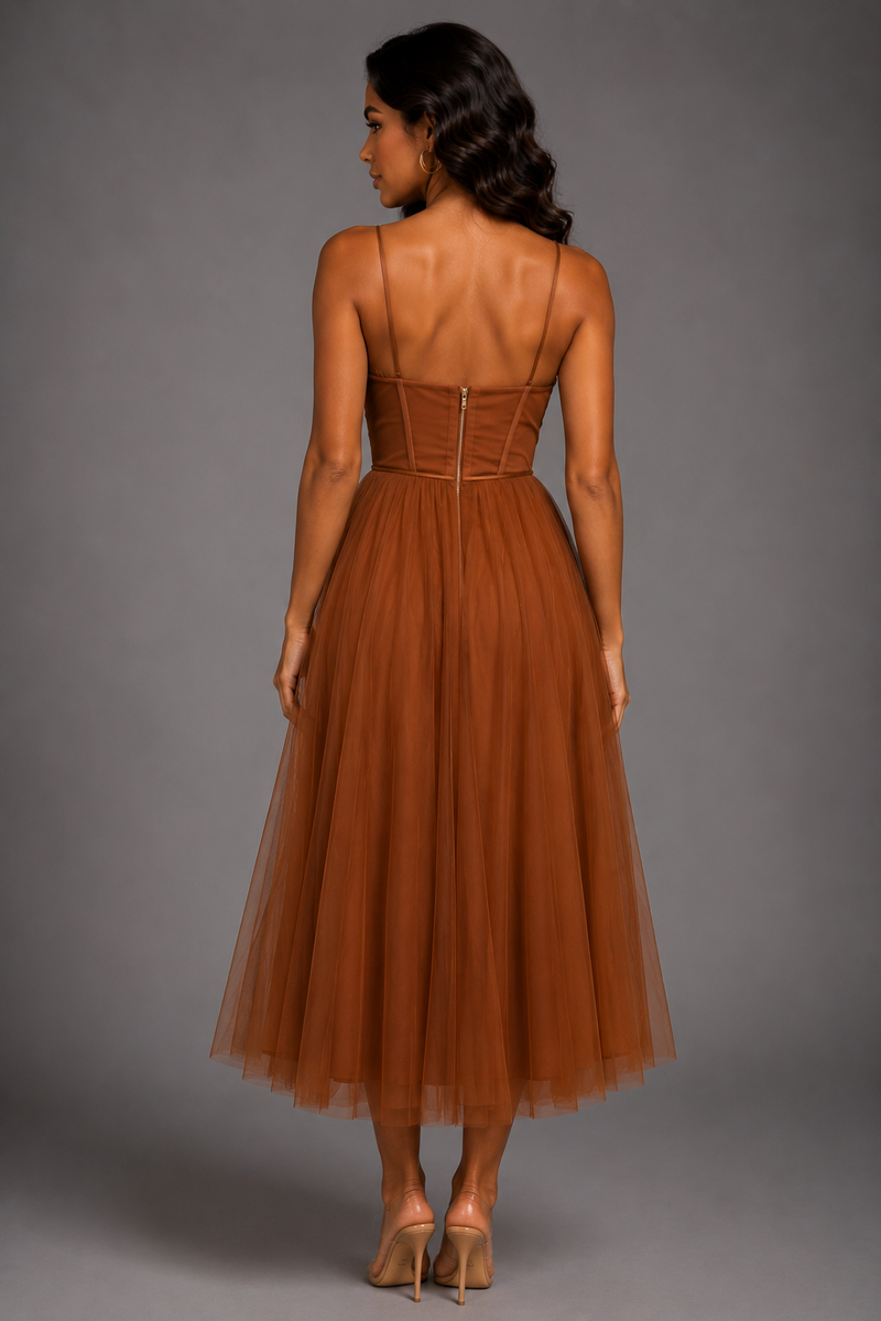 Woman wearing a brown dress with thin straps on a gray background