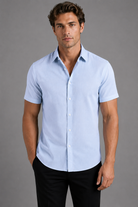 Man wearing a light blue short-sleeve shirt against a gray background