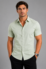 Man wearing a light green shirt and black pants against a gray background