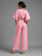 Woman wearing a pink jumpsuit against a gray background