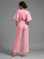 Woman wearing a pink jumpsuit against a gray background