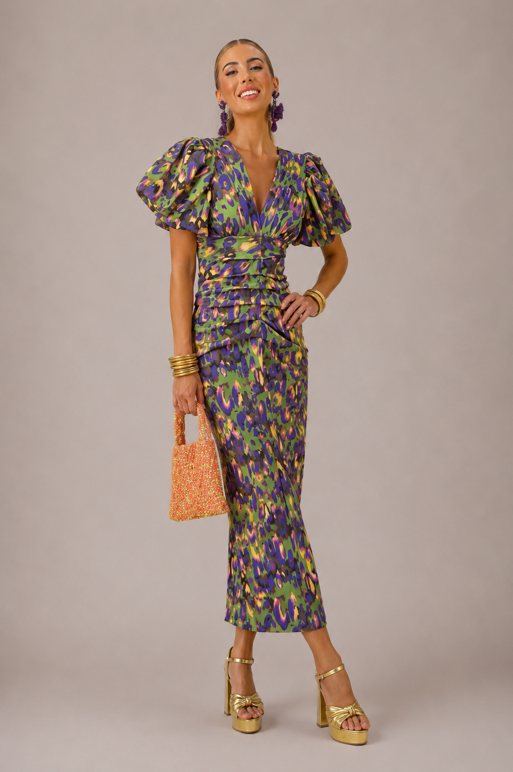 Woman wearing a colorful patterned dress with puffed sleeves against a plain background