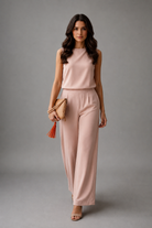 Woman wearing a pink outfit with a clutch against a gray background