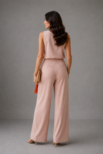 Woman wearing a pink outfit with wide-leg pants against a gray background