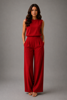 Woman wearing a red jumpsuit against a gray background