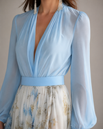 Light blue dress with long sleeves and a floral skirt on a neutral background