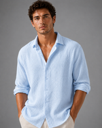 Man wearing a light blue shirt with rolled-up sleeves against a gray background