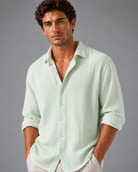 Man wearing a light green button-up shirt against a gray background