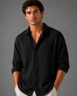 Man wearing a black textured shirt against a gray background