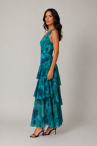 Woman wearing a teal and blue patterned dress on a plain background
