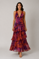 Woman wearing a tiered, floral-patterned dress on a plain background