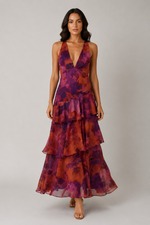 Woman wearing a tiered, floral-patterned dress on a plain background