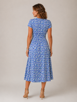 Woman wearing a blue floral dress against a plain background