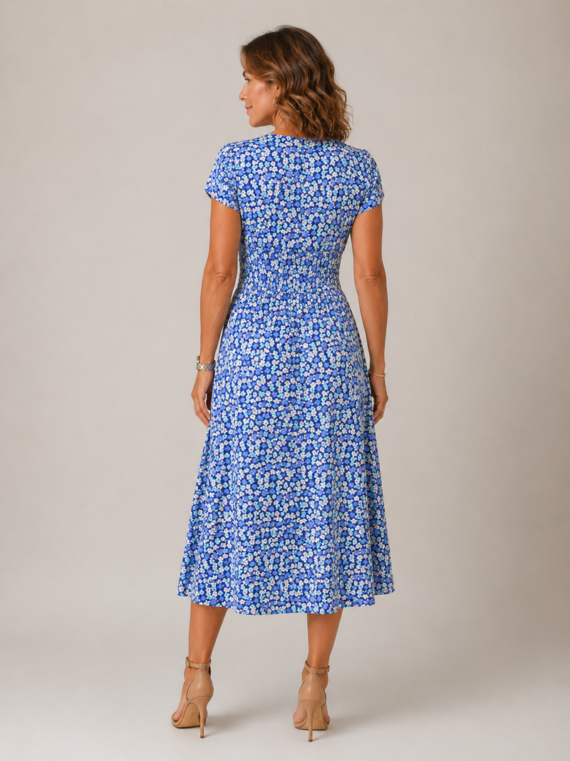 Woman wearing a blue floral dress against a plain background