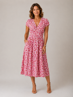 Woman wearing a pink floral dress against a plain background
