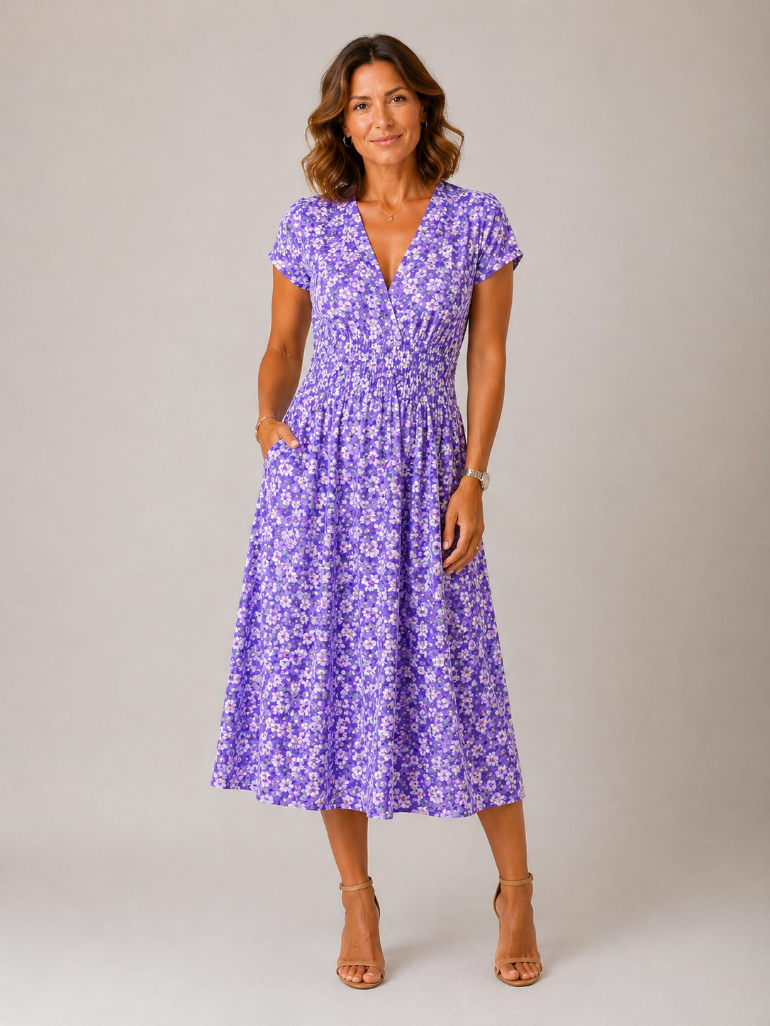 Woman wearing a purple floral dress against a plain background