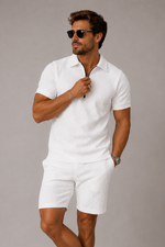 Man wearing a white outfit with sunglasses on a plain background