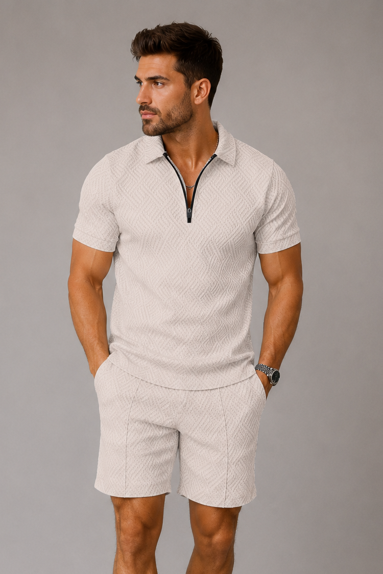 Man wearing a beige polo shirt and shorts with white sneakers on a gray background